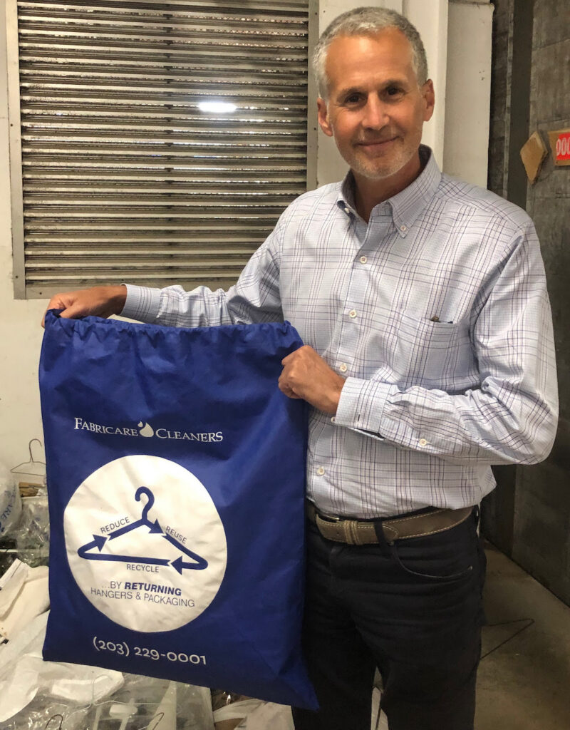 fabricare cleaners owner holding recycling bag